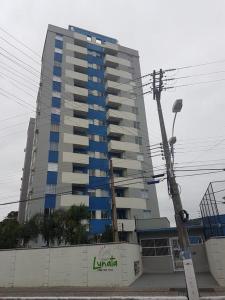un edificio alto con ventanas azules delante de él en Apartamento em Penha SC, en Penha