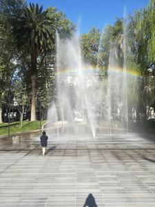 a person standing in front of a fountain with a rainbow at Monoambiente en Mendoza in Mendoza +10 photos