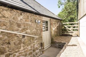 a stone house with a white door and a fence at Shellbraes Studio in Ryal
