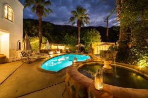 a swimming pool with palm trees and a house at Korakia Pensione in Palm Springs