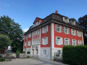 ein rot-weißes Gebäude mit weißen Fenstern in der Unterkunft Villa Jakobsbrunnen in Winterthur