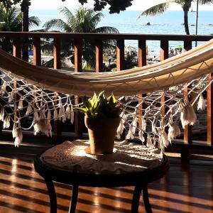 a hammock on a balcony with a plant on a table at Pousada Funny in Morro de São Paulo