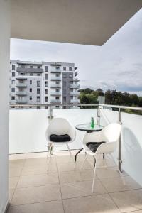 a balcony with white chairs and a table and a building at Apartament Sweet House in Olsztyn