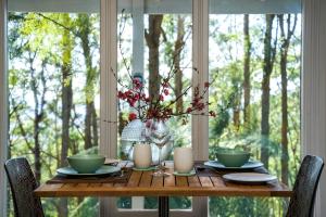 a table with two cups and a vase with flowers at Olinda Forest Retreat with Spa in Olinda