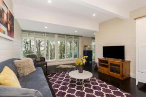 a living room with a couch and a tv at Olinda Forest Retreat with Spa in Olinda