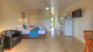 a bedroom with a bed and a chair and a refrigerator at Sky View Units Bowen in Bowen