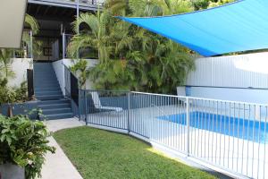 a blue fence in front of a house with a swimming pool at Gecko Guest House in Cooktown