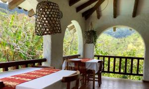 a room with two tables and a balcony with windows at Hacienda Primavera Wilderness Ecolodge in Ambuquí