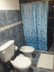 baño con aseo y cortina de ducha azul en Hospedaje Doña Velia en Purmamarca