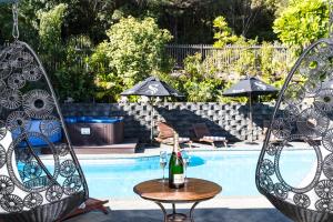 2 Stühle und ein Tisch mit einer Flasche Champagner neben dem Pool in der Unterkunft Grand Mercure Puka Park Resort in Pauanui