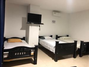two beds in a room with a tv on the wall at Hostal Central Beach in San Andrés