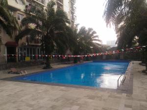 a swimming pool with a string of flags next to a building at Pool View 2BR Mutiara Bekasi Apartment By Travelio in Bekasi