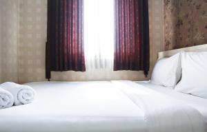 a bedroom with a bed with two towels on it at Pool View 2BR Mutiara Bekasi Apartment By Travelio in Bekasi +7 photos