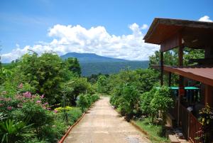 a dirt road next to a house with mountains in the background at Prue Sa Raj in Phetchabun