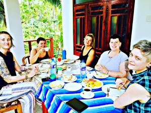 a group of people sitting around a table eating food at Sigiri Rainbow Lodge in Sigiriya +86 photos