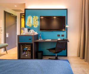 a bedroom with a blue wall with a tv and a chair at Best Western Hotel Cristallo in Rovigo