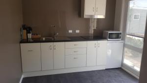 a kitchen with white cabinets and a sink and a microwave at 3107 Estate in Irymple