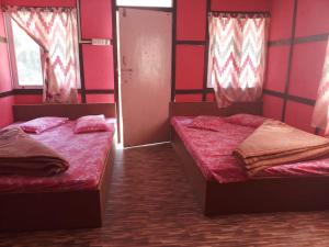 two beds in a room with red walls at Vamoosetrail Reshi River Cottage in Pedong