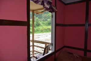 a window in a room with a view of a porch at Vamoosetrail Reshi River Cottage in Pedong