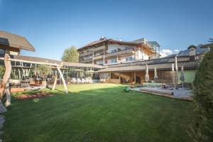 a large yard with a playground and a building at Hotel Fameli in Valdaora