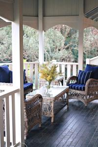 un porche con sillas de mimbre y una mesa en un porche en Bangalow Guesthouse, en Bangalow