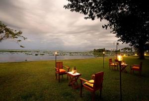 a group of tables and chairs next to a body of water at Punnamada Resort in Alleppey