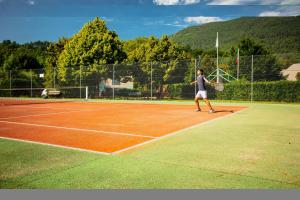 a woman is playing tennis on a tennis court at Camping le Pré Morjal in Ispagnac