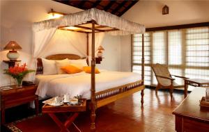 a bedroom with a canopy bed and a table at Punnamada Resort in Alleppey