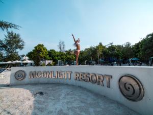 una mujer parada en un cartel en una playa en Moonlight Resort, en Koh Rong Sanloem