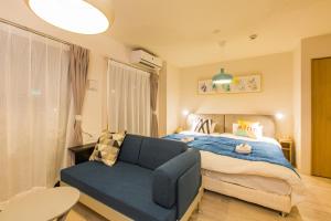 een slaapkamer met een blauwe bank voor een bed bij Sky Living Namba in Osaka