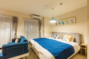 a bedroom with a large bed and a blue chair at Sky Living Namba in Osaka