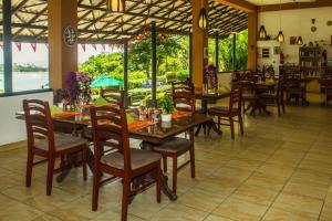 a restaurant with wooden tables and chairs and windows at Hotel Panorama in Unawatuna