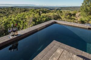 a swimming pool with two glasses of wine and a table with wine glasses at Kariega Game Reserve Ukhozi Lodge in Kenton on Sea