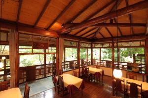 a dining room with tables and chairs and windows at 小さなホテルセラヴィ in Nagatoro