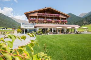 a building with a balcony with flowers on it at Vitalpina Hotel Magdalenahof in Santa Maddalena in Casies