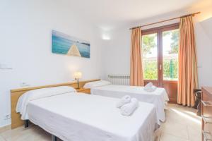 two beds in a room with a window at Ca N'Estel in Cala d´Or