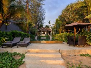 a patio with chairs and an umbrella and stairs at Infinity Blue Phuket by Elite Havens in Natai Beach