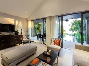 a living room with a couch and a tv at Infinity Blue Phuket by Elite Havens in Natai Beach