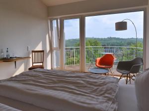 a bedroom with a bed and chairs and a balcony at Am Paradies in Müllheim