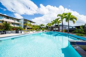 a large swimming pool with palm trees and buildings at 3 Bedroom Ultimate Luxury Waterfront in Cannonvale