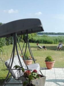 a porch with a chair and plants and a person laying on a bench at Pension Am Bodden in Ribnitz-Damgarten