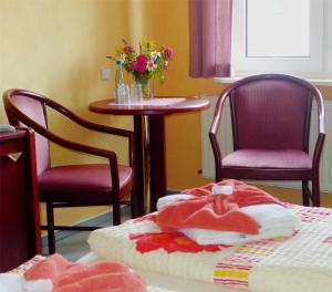リーブニッツ・ダムガルテンにあるPension Am Boddenの椅子2脚、テーブル1台、ベッド1台が備わる客室です。