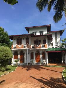 una gran casa blanca con un patio de tierra rojo en Accoma Villa, en Hikkaduwa