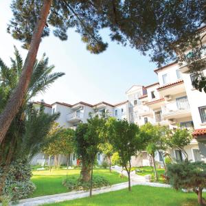 ein großes Apartmenthaus mit Bäumen davor in der Unterkunft Paloma Marina Suites - Adult Only in Kusadası