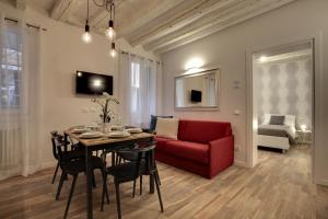 Una sala de estar con una mesa y un sofá rojo. en Castello - Laguna Luxury Residence by Wonderful Italy, en Venecia
