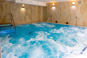 een groot zwembad met blauw water in een kamer bij Bástya Konferencia és Wellness Hotel in Miskolctapolca