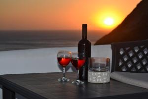 dos copas de vino sentadas en una mesa con una botella de vino en Golden Beach Resort Anafi en Anafi
