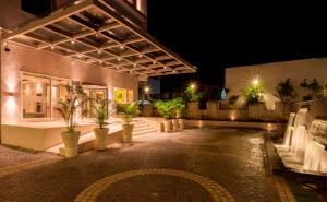 Lemon Tree Hotel Lucknow في لاكناو: مبنى به نباتات الفخار في ساحة الفناء في الليل