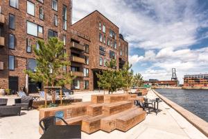 a building with benches and tables next to the water at STAY Seaport in Copenhagen