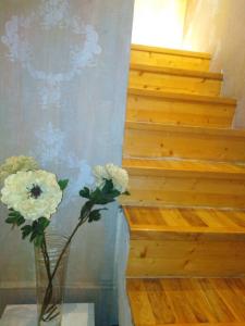 un jarrón con flores sentado en una mesa junto a las escaleras en Apartments Carica, en Novi Sad